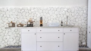 A kitchen with a white cabinet and a stone backsplash. - CALM VILLA SEMINYAK (Seminyak)