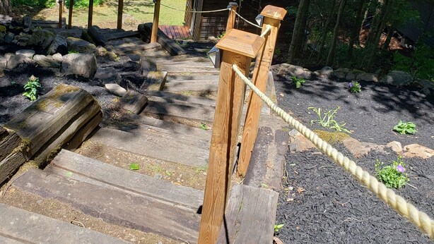 A wooden staircase leading to a dock over a lake, surrounded by trees and a small wooden structure.