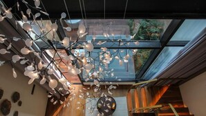 Un interior moderno con una lámpara de techo original, una escalera y vistas a través de un techo de cristal.