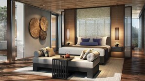 Un dormitorio moderno con una cama grande, un sofá y una mesita con un hervidor. Hay piezas de arte decorativas en la pared y una ventana con vistas.