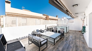 Una terraza en la azotea con mobiliario exterior, una parrilla y vistas panorámicas de la ciudad.