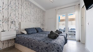 Un dormitorio con colcha estampada, mesita de noche, lámpara de pared y vistas al exterior.