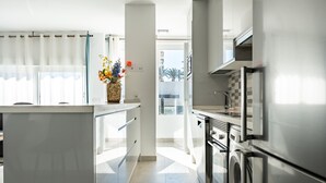 Una cocina moderna con una isla central, electrodomésticos de acero inoxidable y vistas al exterior.