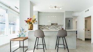 Una cocina moderna con dos taburetes de bar, una mesita pequeña y un jarrón decorativo con flores.