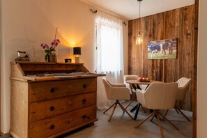 Un coin repas comprenant une commode en bois, une table avec des chaises et un tableau accroché au mur.