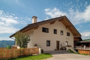 Un bâtiment à deux étages, doté d’un toit en pente, d’une clôture en bois et d’un petit jardin.