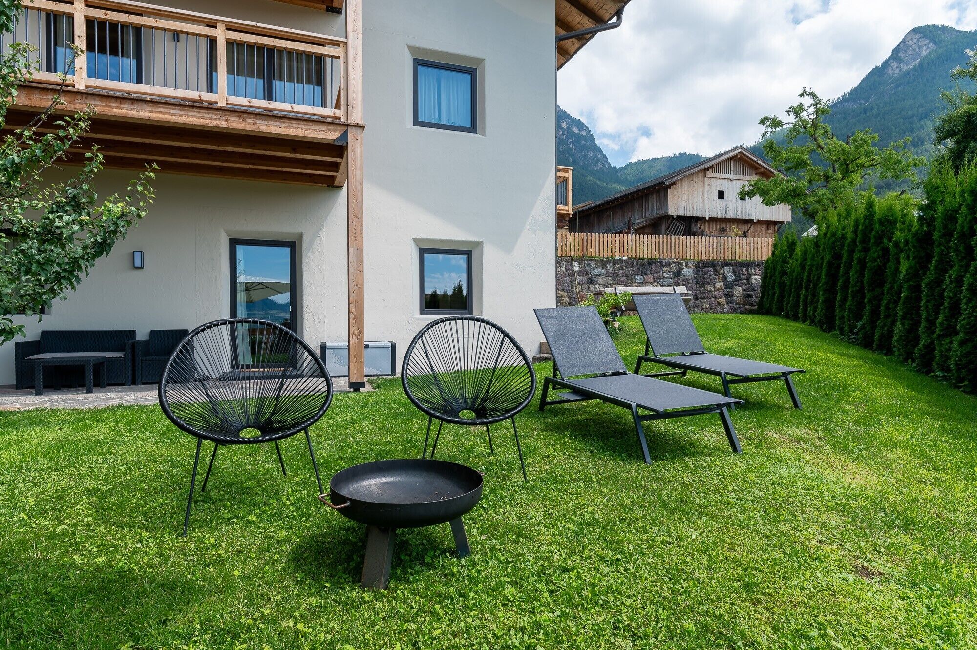 A modern building with a balcony, a grassy yard, and outdoor seating.