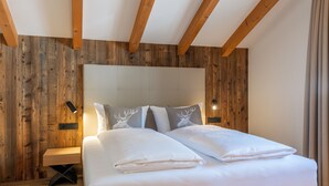 Quarto com cabeceira de madeira, mesa de cabeceira e cama com roupa de cama branca.