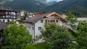 Uma vila de montanha com casas de madeira tradicionais, um pequeno pátio e vista para as montanhas ao redor.