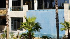 A multi-story hotel with balconies, palm trees, and a pool area. - Si Hotel & Spa (Kuşadası)