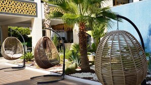 Outdoor wicker chairs, palm trees, and a building with a lattice design. - Si Hotel & Spa (Kuşadası)