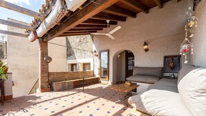 A covered patio with a tiled floor, a wooden bench, a table, and a sofa. - Holiday Home 'Casa Rústica Cal Mian' with Mountain View, Wi-Fi and Air Conditioning (Almoster)