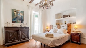 A bedroom with a bed, bedside tables, a dresser, a chandelier, and a painting on the wall. - Holiday Home 'Casa Rústica Cal Mian' with Mountain View, Wi-Fi and Air Conditioning (Almoster)