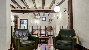 A room with two green leather armchairs, a small round table, and a view of a dining area through a glass door. - Holiday Home 'Casa Rústica Cal Mian' with Mountain View, Wi-Fi and Air Conditioning (Almoster)