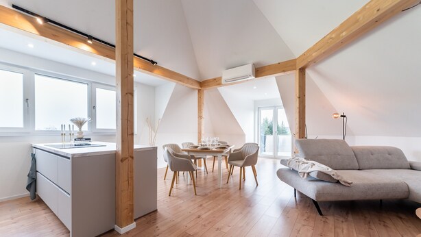 Une cuisine moderne avec un îlot central, un coin repas avec une table ronde et des chaises, un canapé et de grandes fenêtres.
