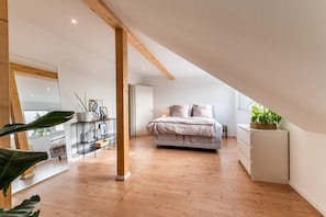 A modern bedroom with a wooden ceiling, a bed, a white dresser, and a plant. - Apartment 'N8quartier' with Balcony, Wi-Fi and Air Conditioning (Bannewitz)