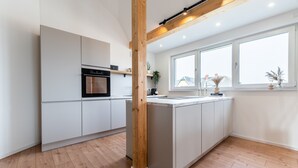 Une cuisine moderne avec des meubles blancs, un îlot central et une grande fenêtre.