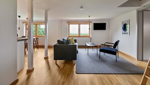 A modern living room with a sofa, a chair, a small table, and a large window.