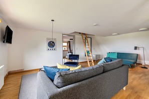 A living room with a grey sofa, a blue chair, and a teal sofa. - ‘ Stille des Nordens ’ is a spacious holiday flat approx. 68sqm 3 persons on the upper floor (Pellworm)