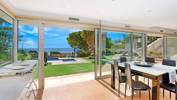 A modern kitchen with a large island, a dining area with a view, and a pool.