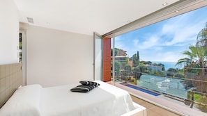 Quarto de hotel com varanda ampla, uma cama e vista para o mar e edifícios.