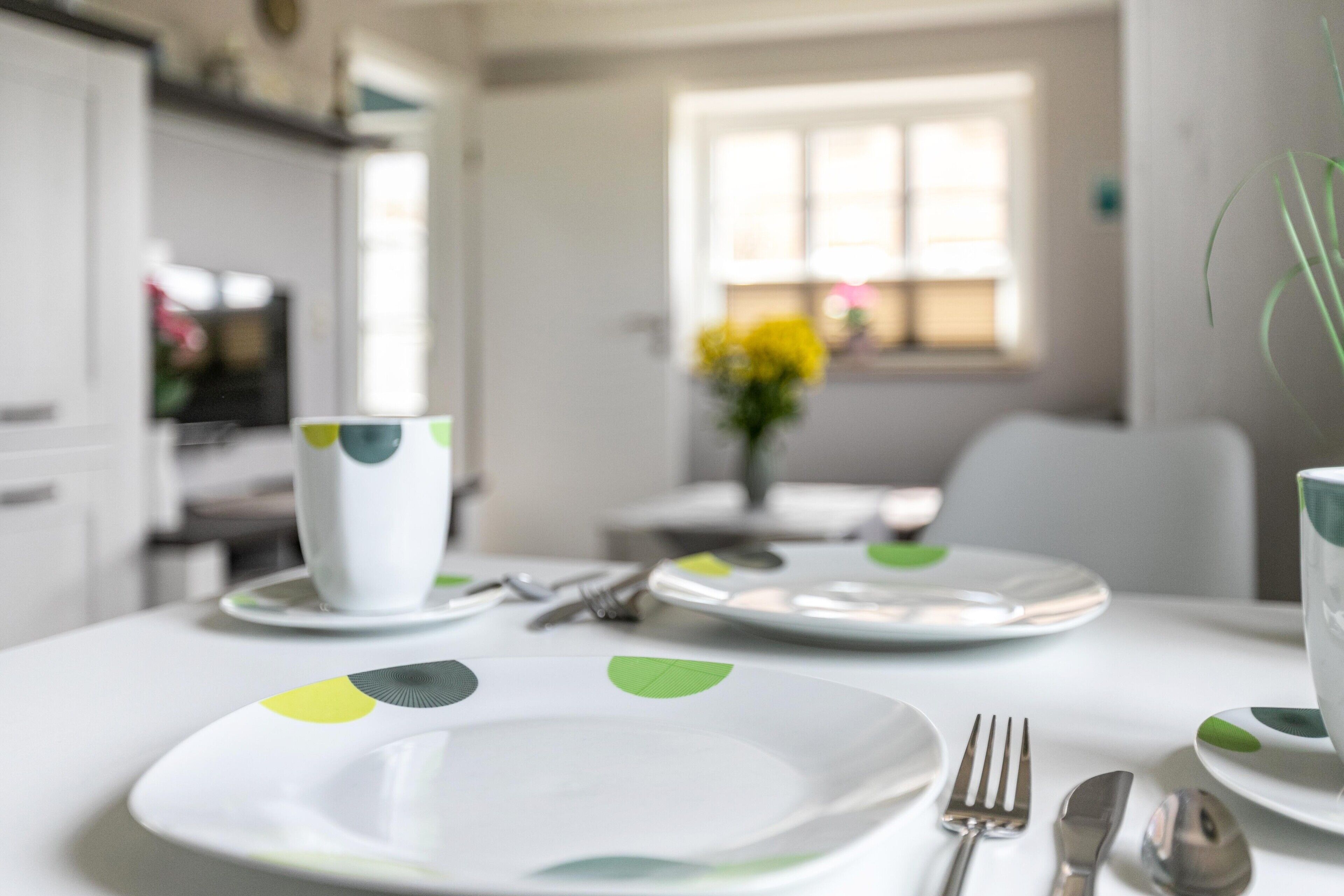Une table à manger avec des assiettes, des couverts et une tasse.