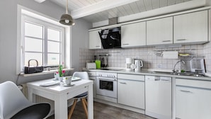 Una cucina moderna con mobili bianchi, forno integrato, lavastoviglie e una finestra che permette l'illuminazione naturale.