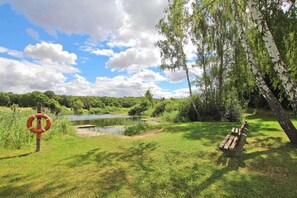 A grassy area with a bench, a lifebuoy, and a body of water. - Holiday Home 'Alter Stall' with Private Terrace, Private Garden and Wi-Fi (Oberuckersee)