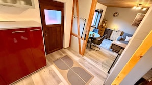 A modern kitchen with a red cabinet, a wooden door, and a dining area with a table and chairs. - Holiday Home 'Alte Schmiede' with Private Terrace and Wi-Fi (Oberuckersee)
