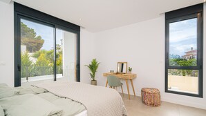 Une chambre à coucher avec un lit, un bureau, une chaise, une plante en pot et une fenêtre.