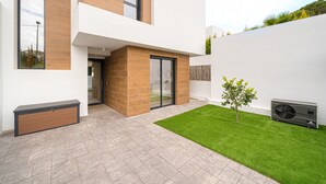 Une maison moderne à deux étages, dotée d’un toit plat, d’une petite pelouse et d’une fenêtre.