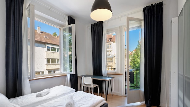 Une chambre à coucher avec un lit, un bureau et une vue sur l’extérieur.