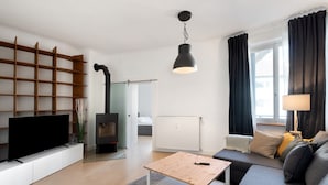 Un salon moderne doté d’un téléviseur à écran plat, d’une table basse en bois, d’un canapé, d’une cheminée et d’une grande fenêtre agrémentée de rideaux.
