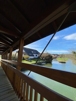 A wooden bridge with a view of a river and houses in the background. - Apartment 'Ruhige Ferienwohnung Im Hegau' with Balcony and Wi-Fi (Volkertshausen)