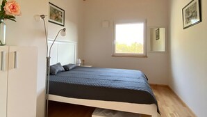 Een slaapkamer met een bed, een bedlampje, een raam en een houten plafond.