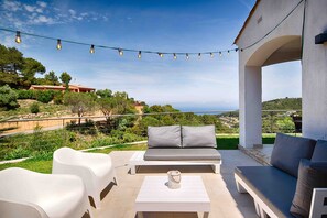 A terrace with outdoor seating, string lights, and a view of the landscape.