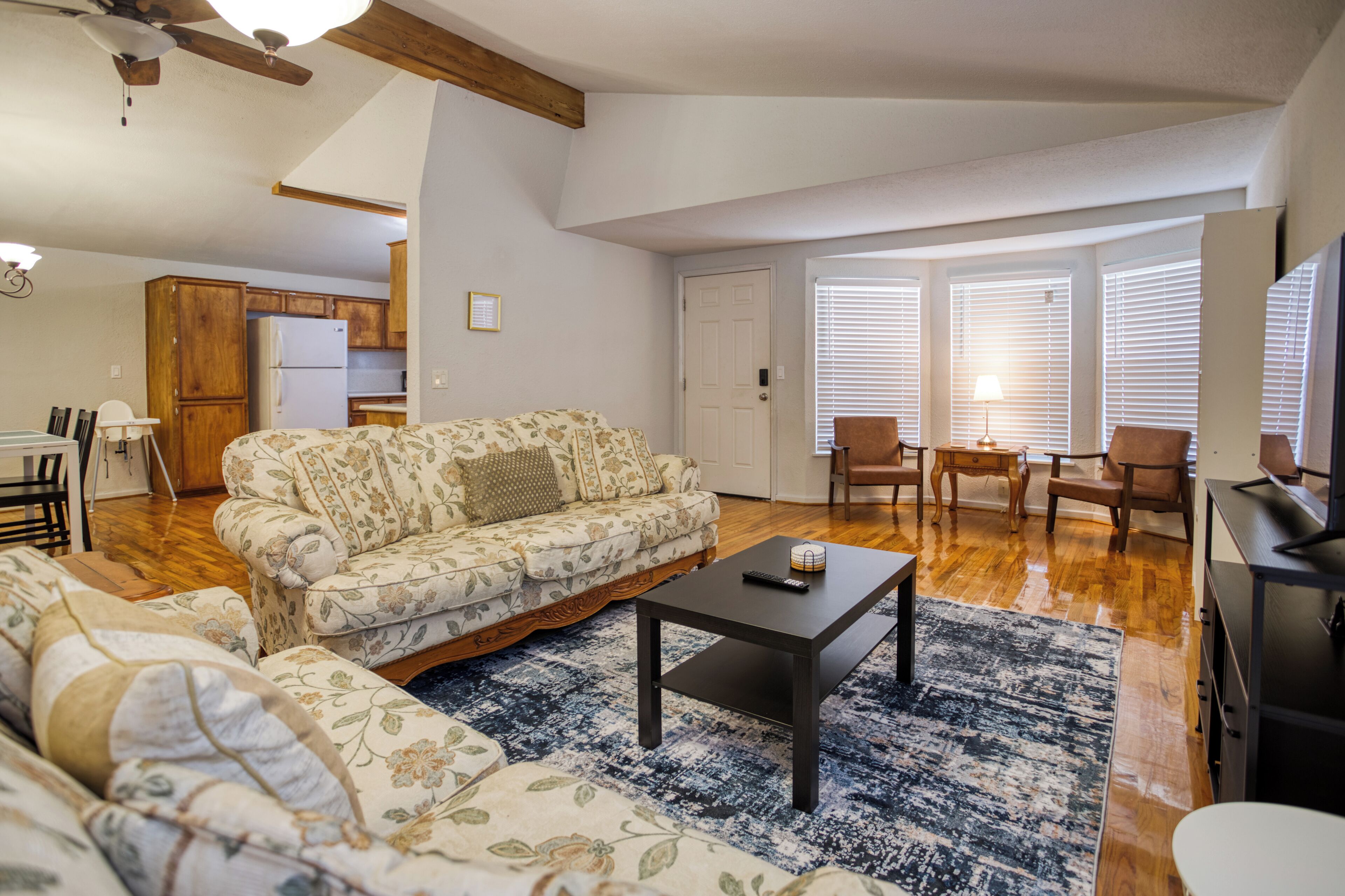 A spacious living area with a sofa, coffee table, and a view of the kitchen and dining area.