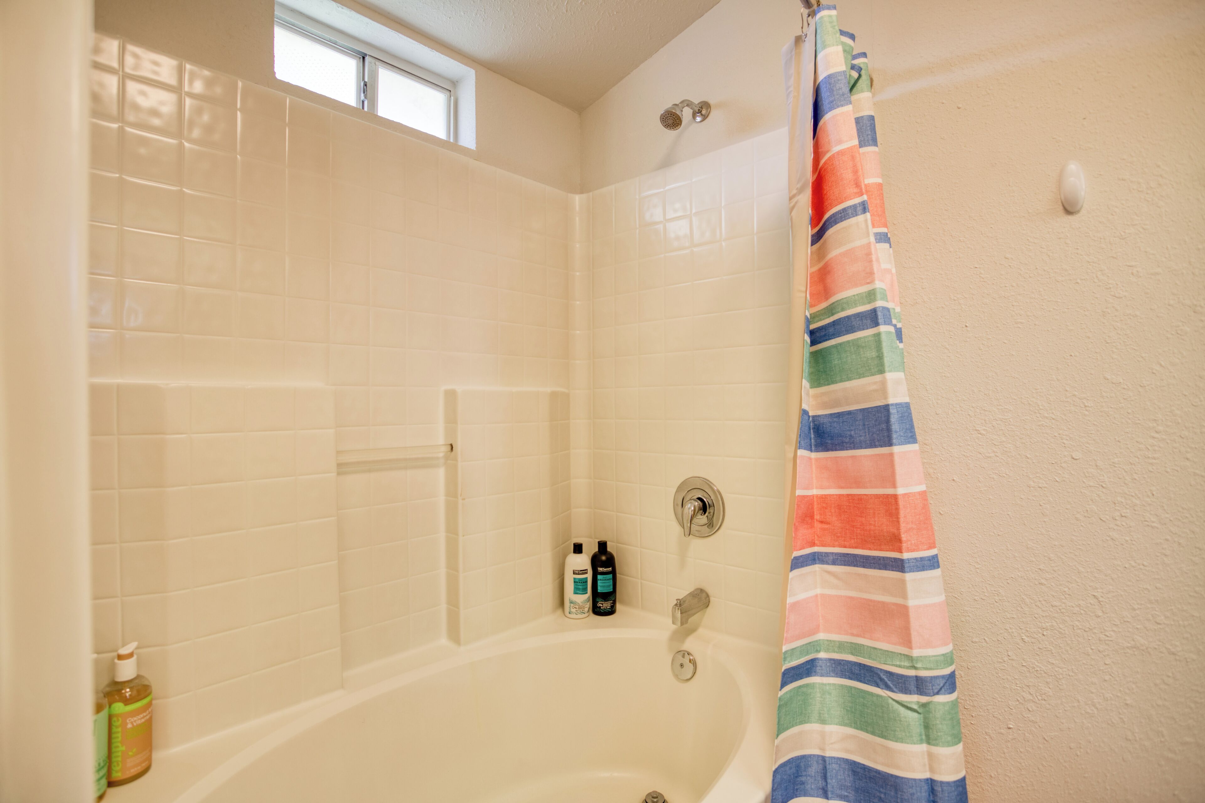 Une salle de bain avec une baignoire, un rideau de douche et des articles de toilette accrochés au mur.