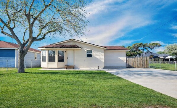 A single-story house with a front porch, a garage, and a fenced yard.