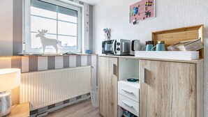 Una cocina con ventana, radiador, un mueble de madera y una repisa con objetos.