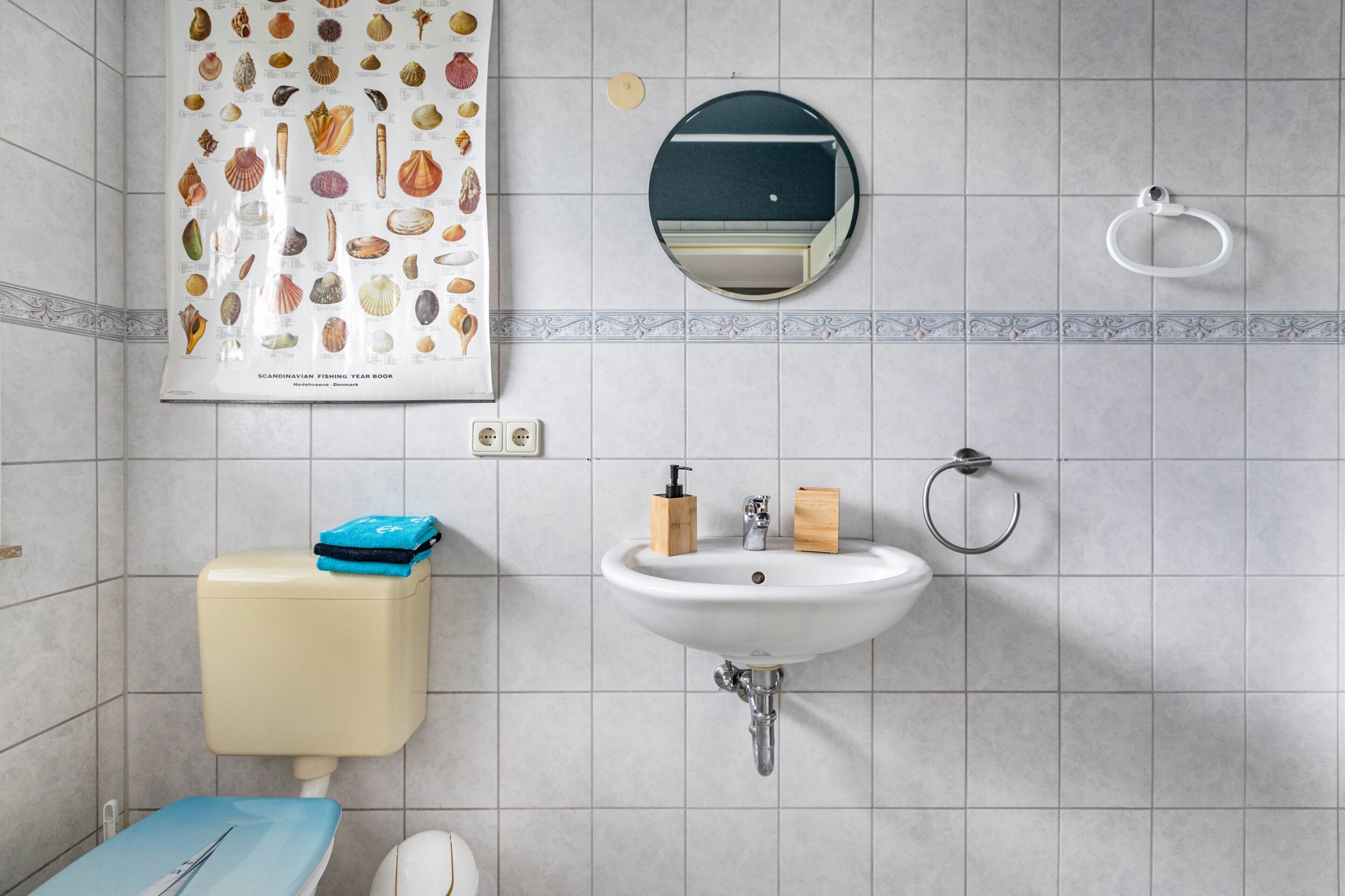 Un bagno con il water, un lavandino, uno specchio e un poster tratto da un annuario di pesca scandinavo.