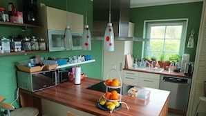 Una cocina con una isla de madera, taburetes de bar, un fregadero y diversos electrodomésticos.