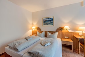 A hotel room with two beds, a nightstand, a desk, and a painting on the wall. - Room 'Aparthotel Am Stadtpark 1106' with Wi-Fi (Bad Sachsa)