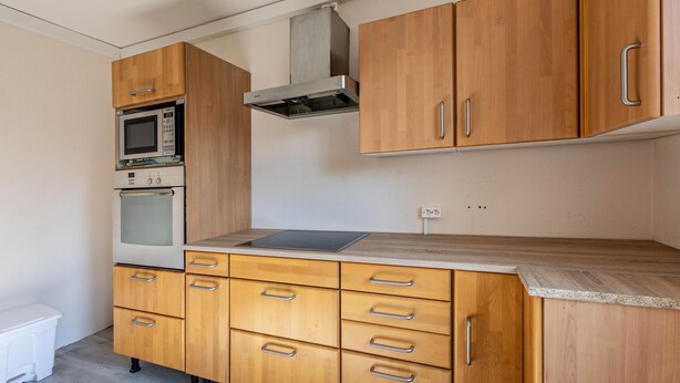 Une cuisine avec des meubles de rangement en bois, un four à micro-ondes, un four traditionnel et un plan de travail.