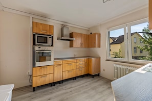 A compact kitchen with wooden cabinets, a microwave, and an oven. - Room 'Aparthotel Am Stadtpark 1106' with Wi-Fi (Bad Sachsa)