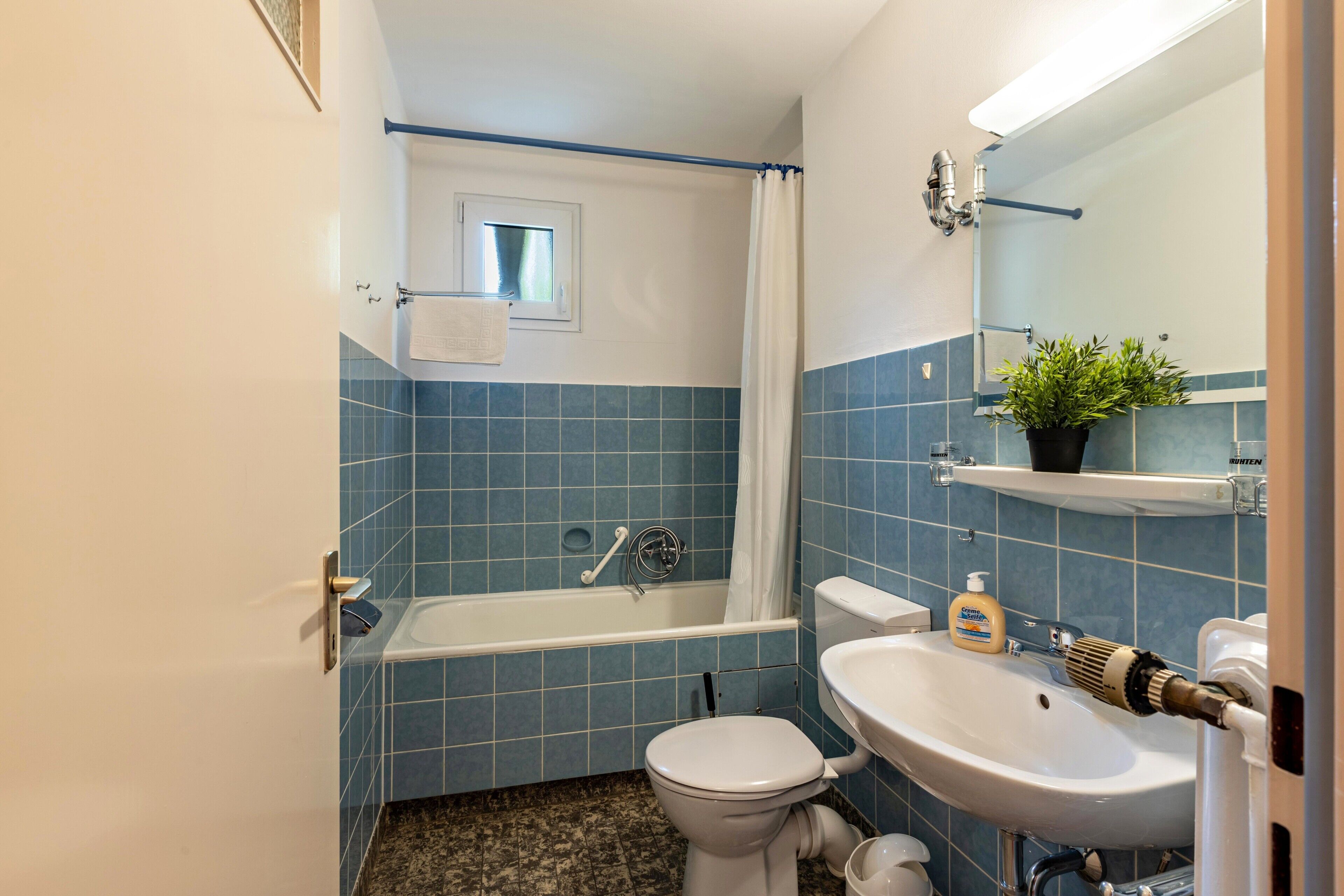 Ein Badezimmer mit Badewanne, Toilette, Waschbecken und einem Fenster.