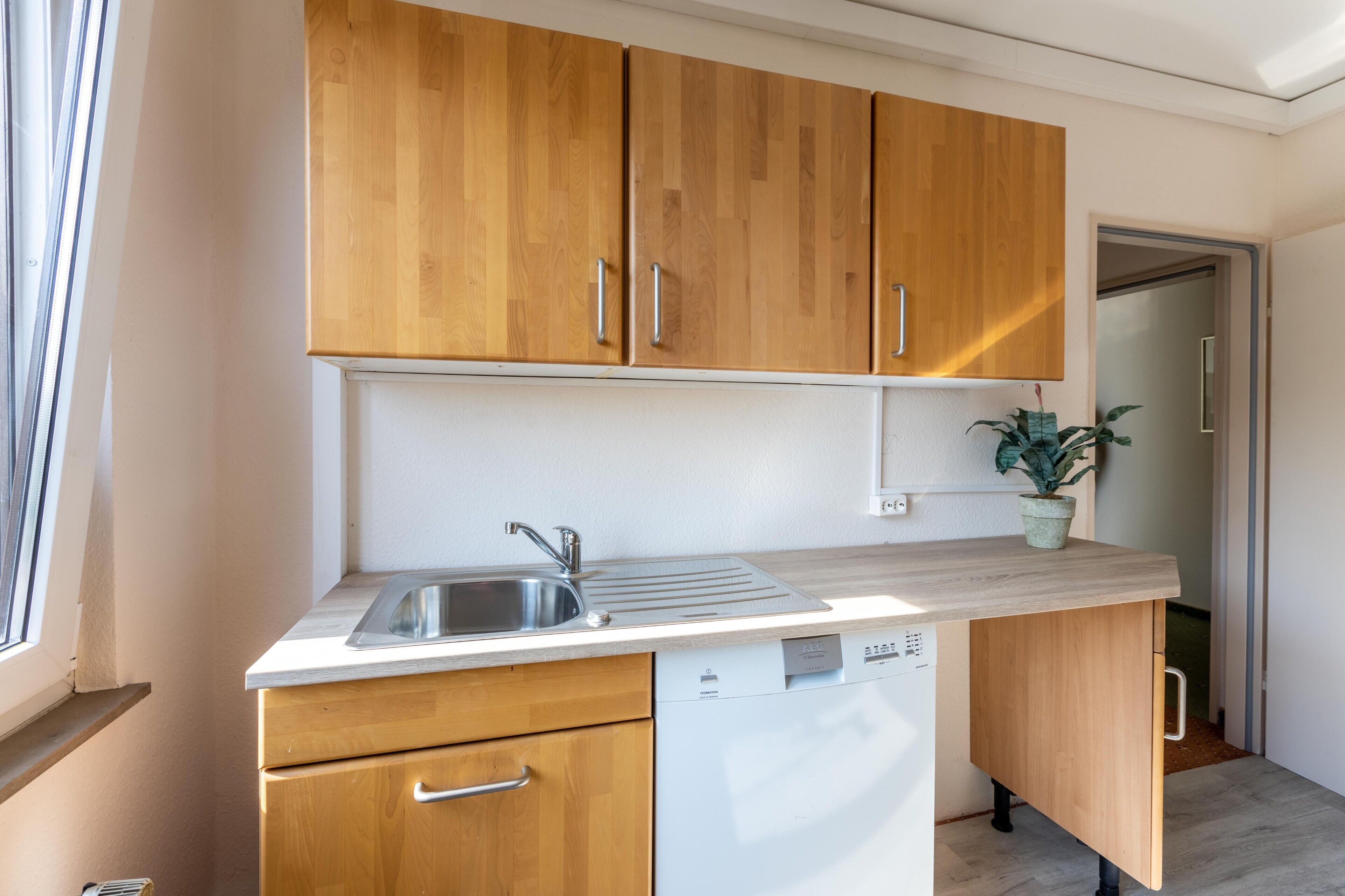 A kitchen with wooden cabinets, a stainless steel sink, and a dishwasher.