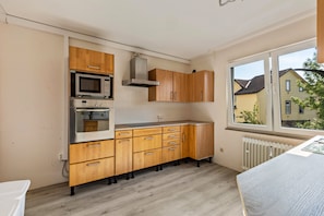 A kitchen with wooden cabinets, a microwave, and an oven.