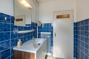 A bathroom with a white sink, blue tiles, a mirror, and a door with a gold accent. - Room 'Aparthotel Am Stadtpark 1110' with Wi-Fi (Bad Sachsa)