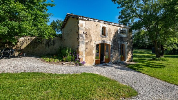 A rustic stone building with a tiled roof, a wooden door, and a small window. - Gîte Le Pigeonnier with Shared Pool, Wi-Fi, and Air Conditioning (Chassaignes)